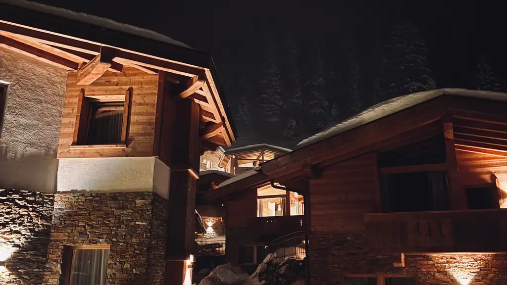 Stone and timber mountain home lit up on a snowy night