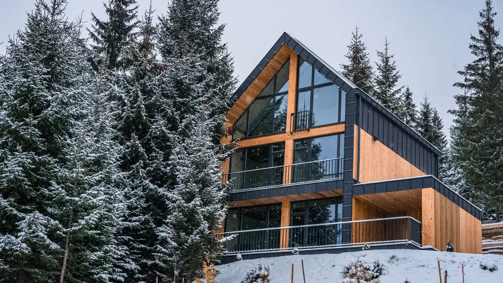 Modern timber-and-glass chalet among snow-covered pines