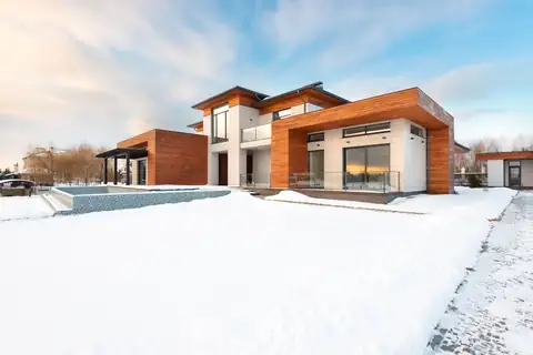 Contemporary wood-clad home with a snow-covered yard